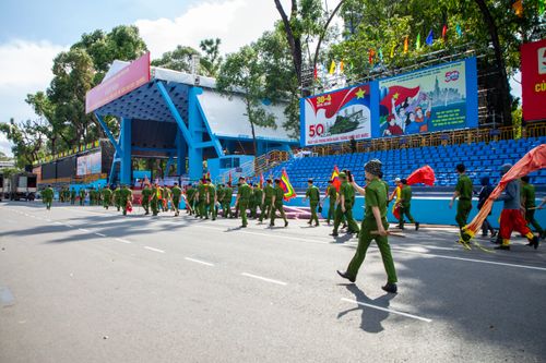 Free Military personnel prepare for a parade with colorful flags in a Vietnam street setting. Stock Photo