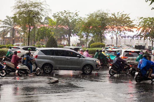 Busy street with motorbikes and cars in heavy rain, city setting.