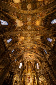 Stunning baroque ceiling in a historic cathedral with intricate frescoes and golden altar.