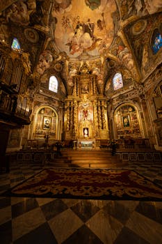 Stunning Baroque church interior featuring ornate gold altar, frescoed ceiling, and intricate architectural details.