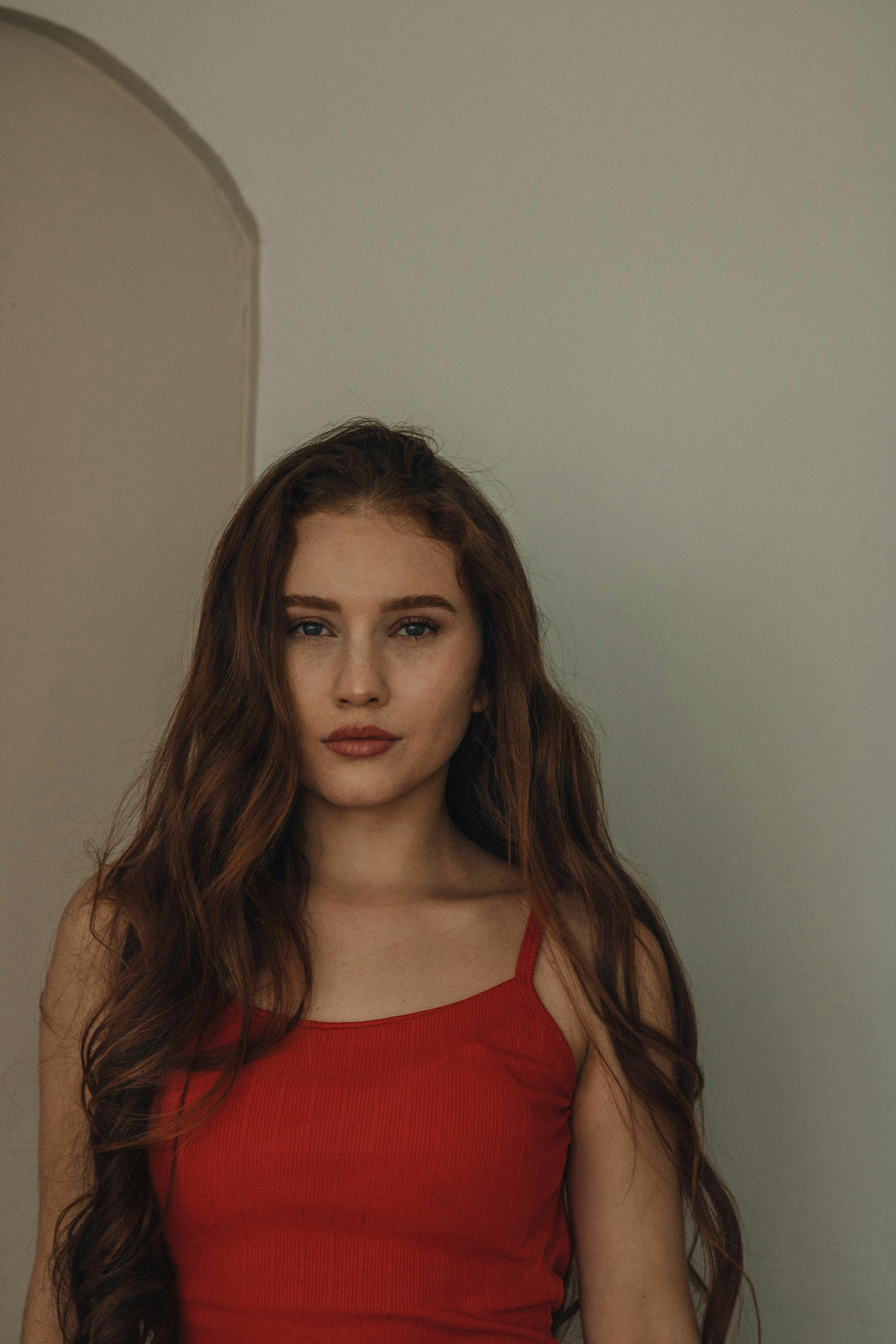 ingyenes Fiatal nő elegáns piros ruhában, semleges háttérrel. Tökéletes divat- és portrétémákhoz. Stockfotó