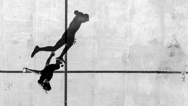 Aerial view of player and shadow on urban court in Buenos Aires.