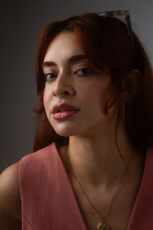 Free Elegant portrait of a woman wearing a pink dress and necklace, with warm lighting. Stock Photo