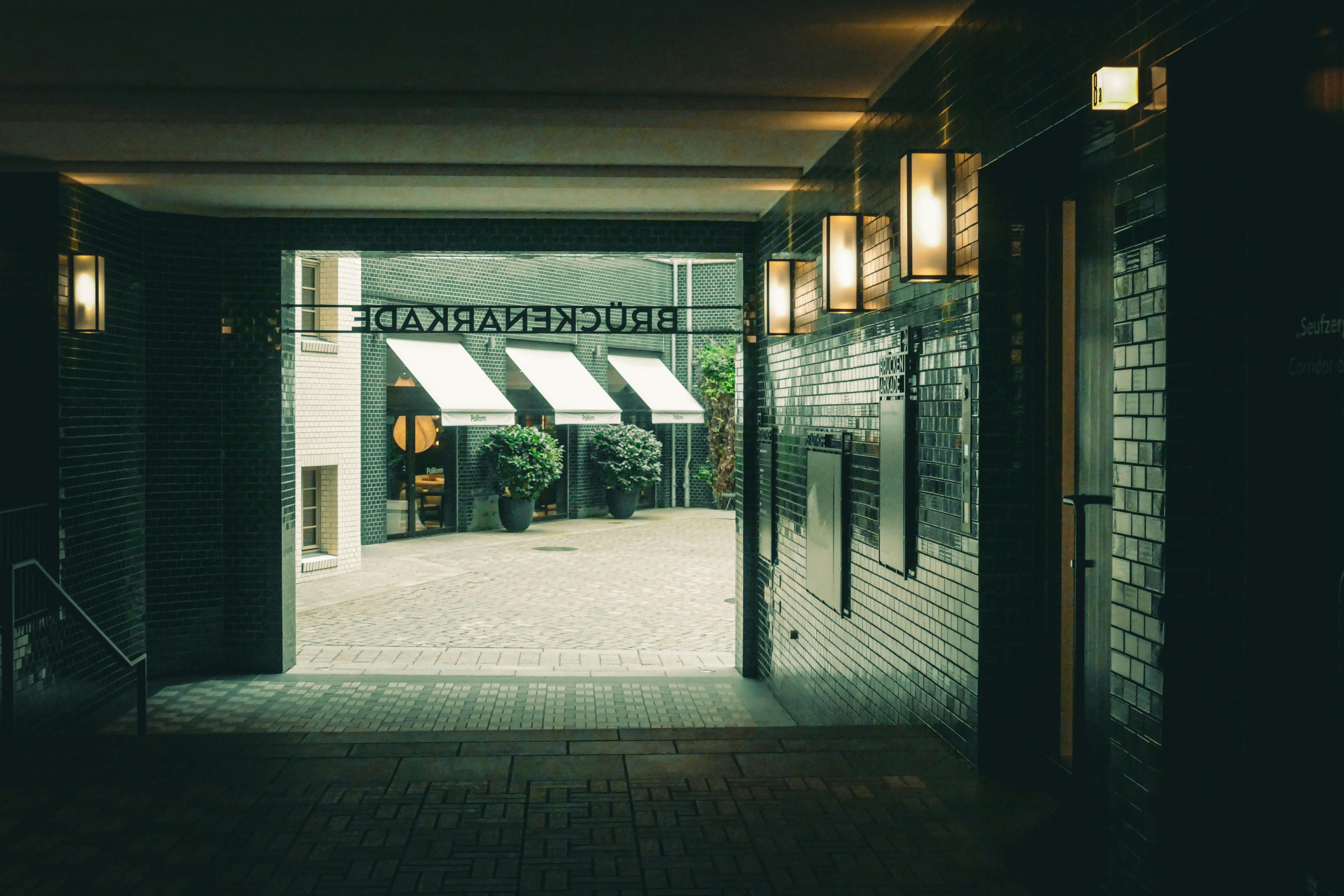 Gratis En koselig utekafé sett gjennom en urban korridor med varm belysning. Arkivbilde