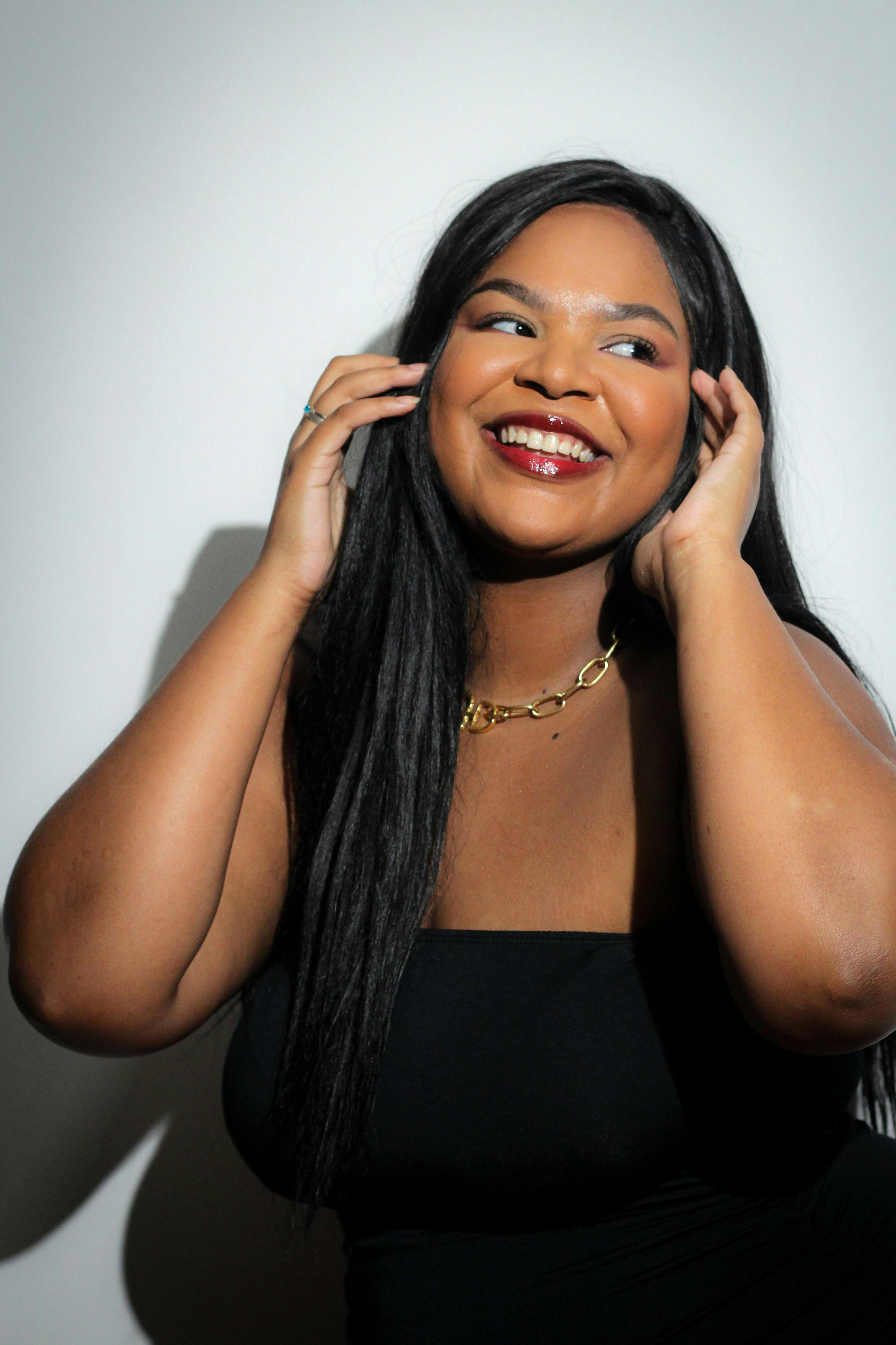 A cheerful woman with long hair smiling against a light background.