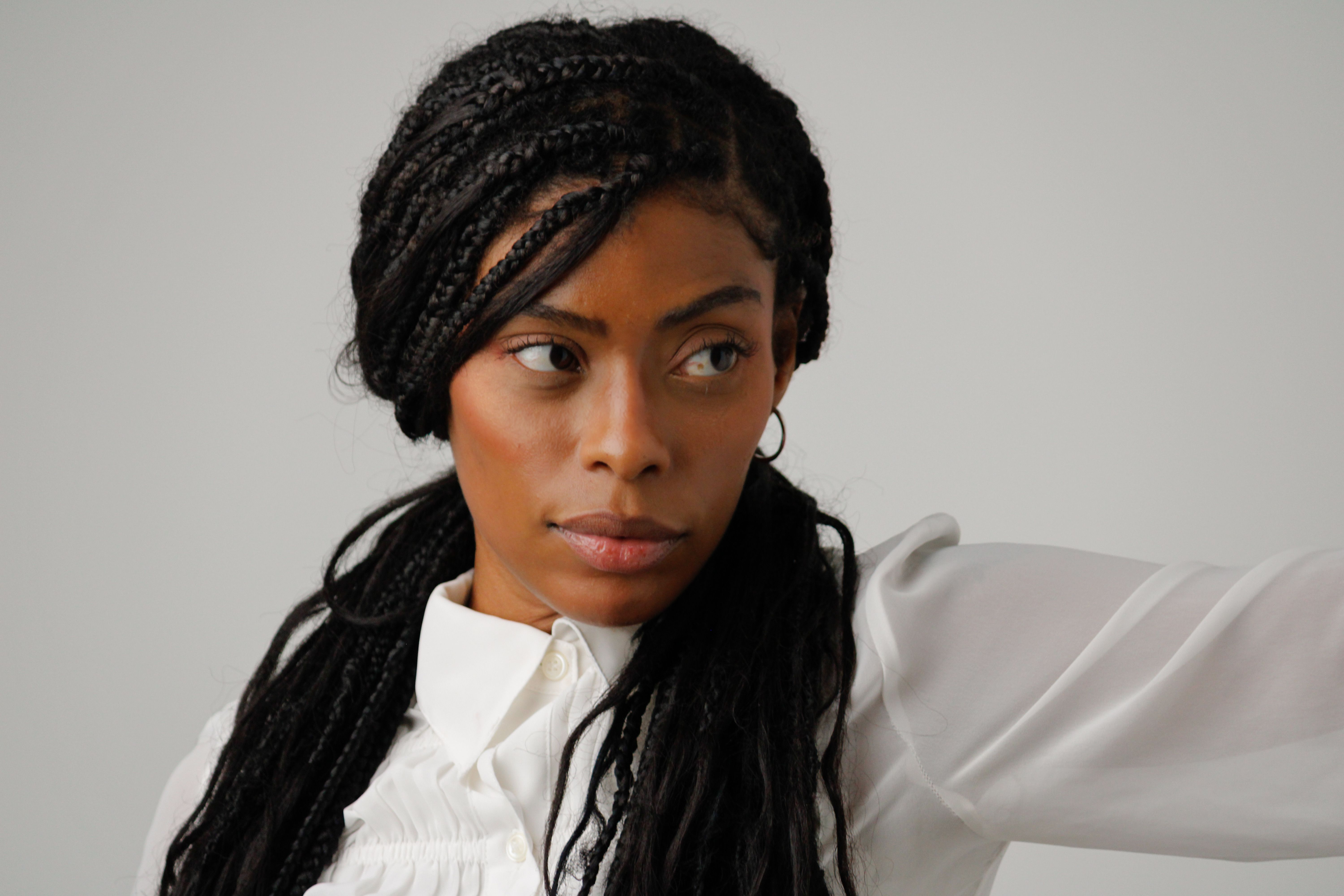 Close-up portrait of a woman with braided hair wearing a white blouse.
