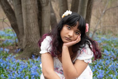 Free A young woman with flowers in her hair, sitting thoughtfully among blooming bluebells. Stock Photo