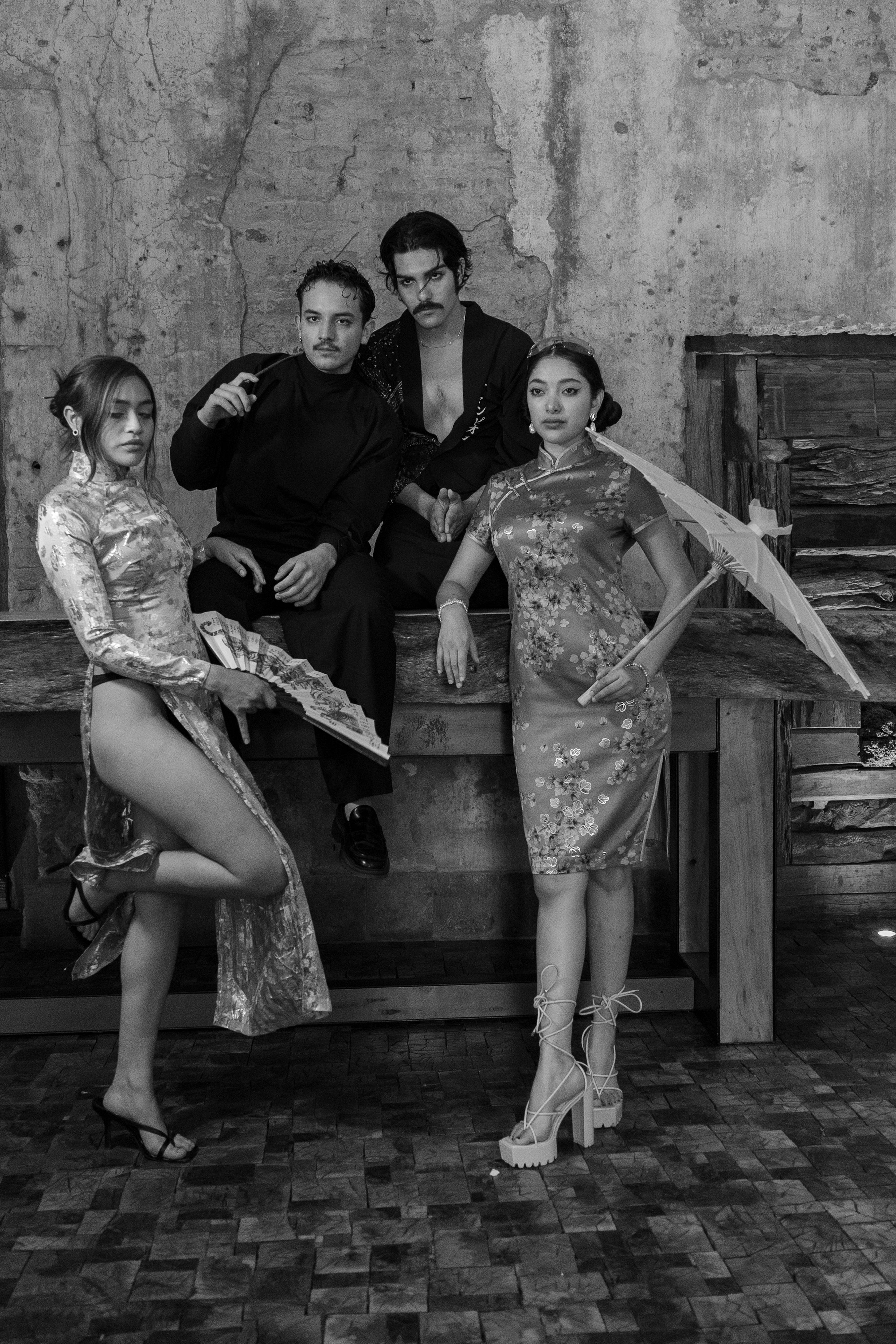 Black and white group portrait of four adults in sophisticated outfits, embodying vintage elegance.