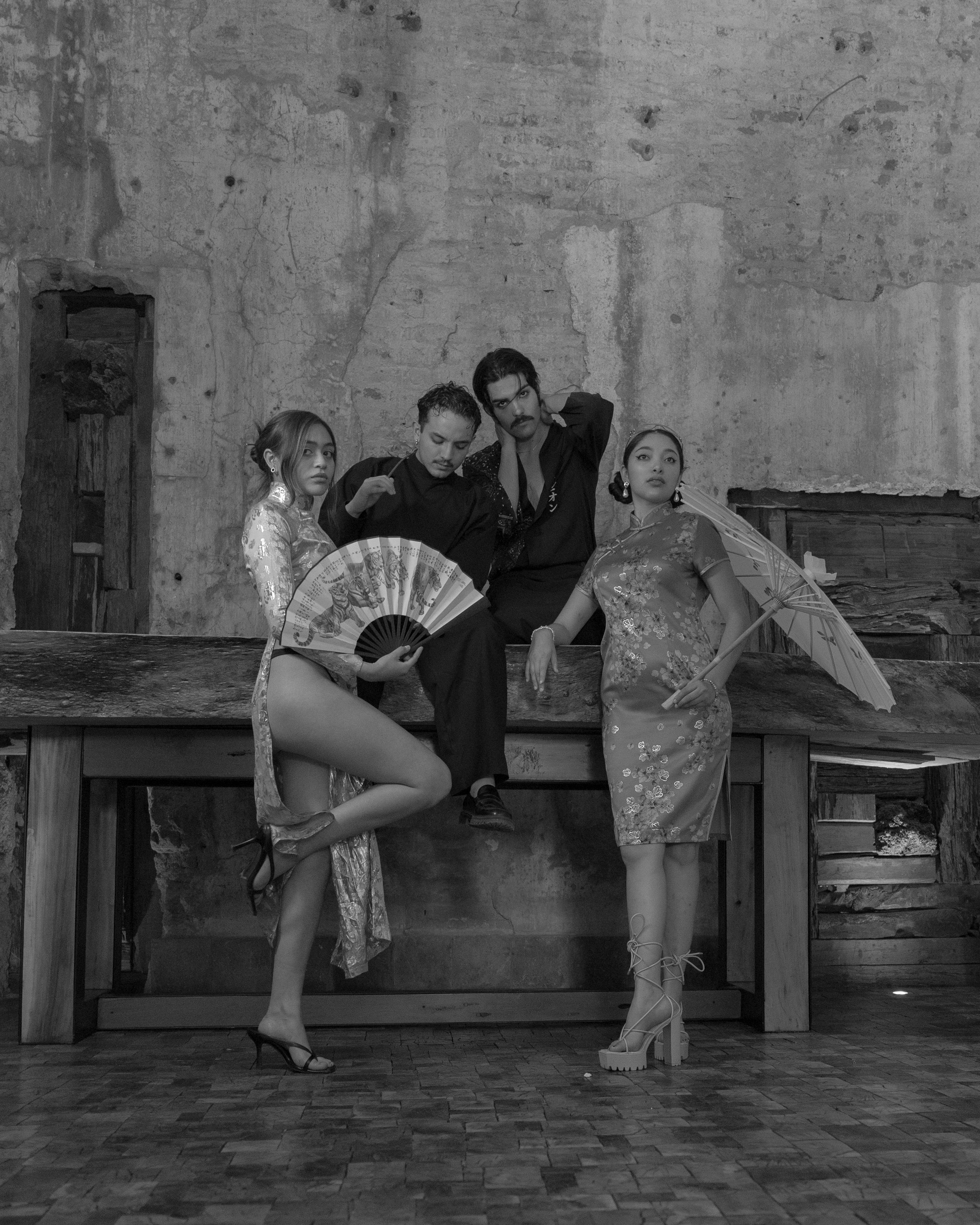 Ücretsiz Vintage kıyafetler giymiş şık bir grup, dokulu bir duvarın önünde iç mekanda poz veriyor. Stok Fotoğraflar