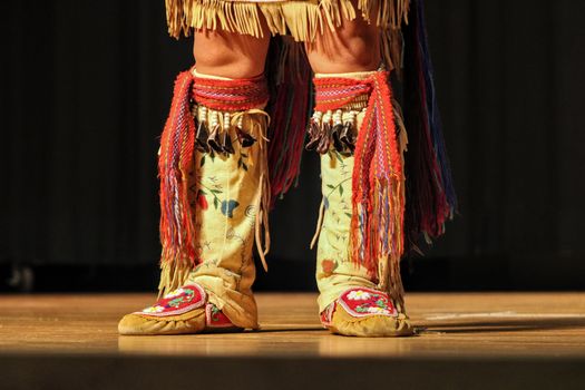 Close-up of traditional Native American dance boots with colorful patterns and fringes.