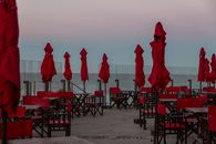 Red umbrellas and chairs on beach terrace at sunset in Mar del Plata, Argentina.