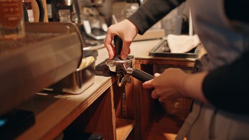 Free Barista tamping coffee grounds in a cozy Tokyo café, highlighting the art of espresso making. Stock Photo