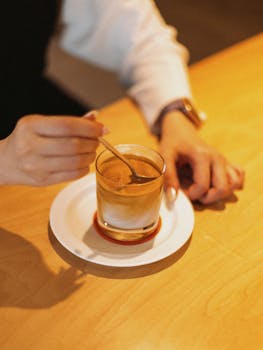 A close-up of a hand stirring coffee in a Shinjuku café, Tokyo, Japan.