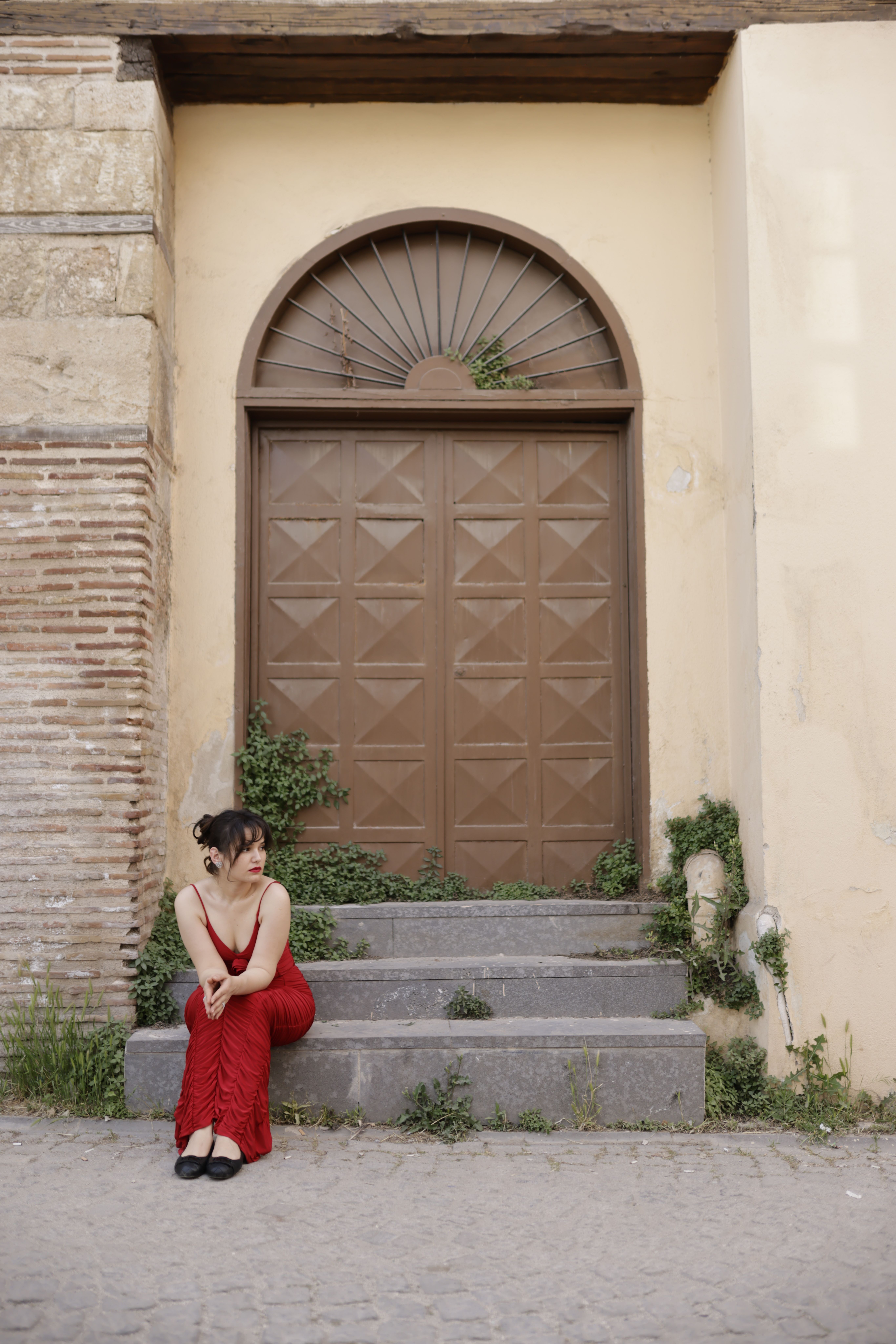 Woman in Red Dress Sitting by Arched Doorway · Free Stock Photo