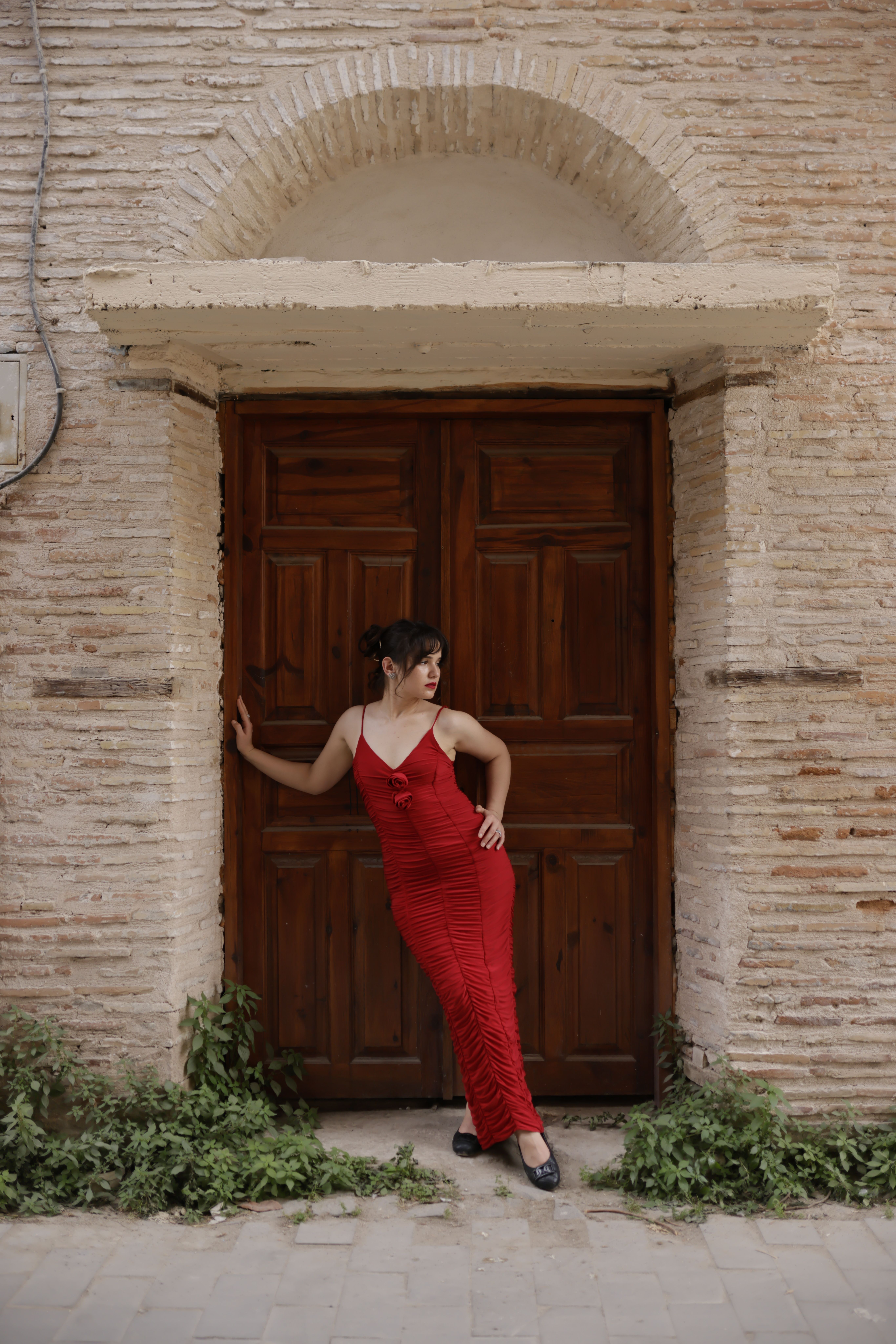 Woman in Red Dress Posing by Rustic Wooden Doorway · Free Stock Photo