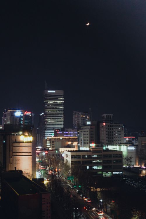 Free Vibrant night view of Seoul's cityscape under a crescent moon. Stock Photo