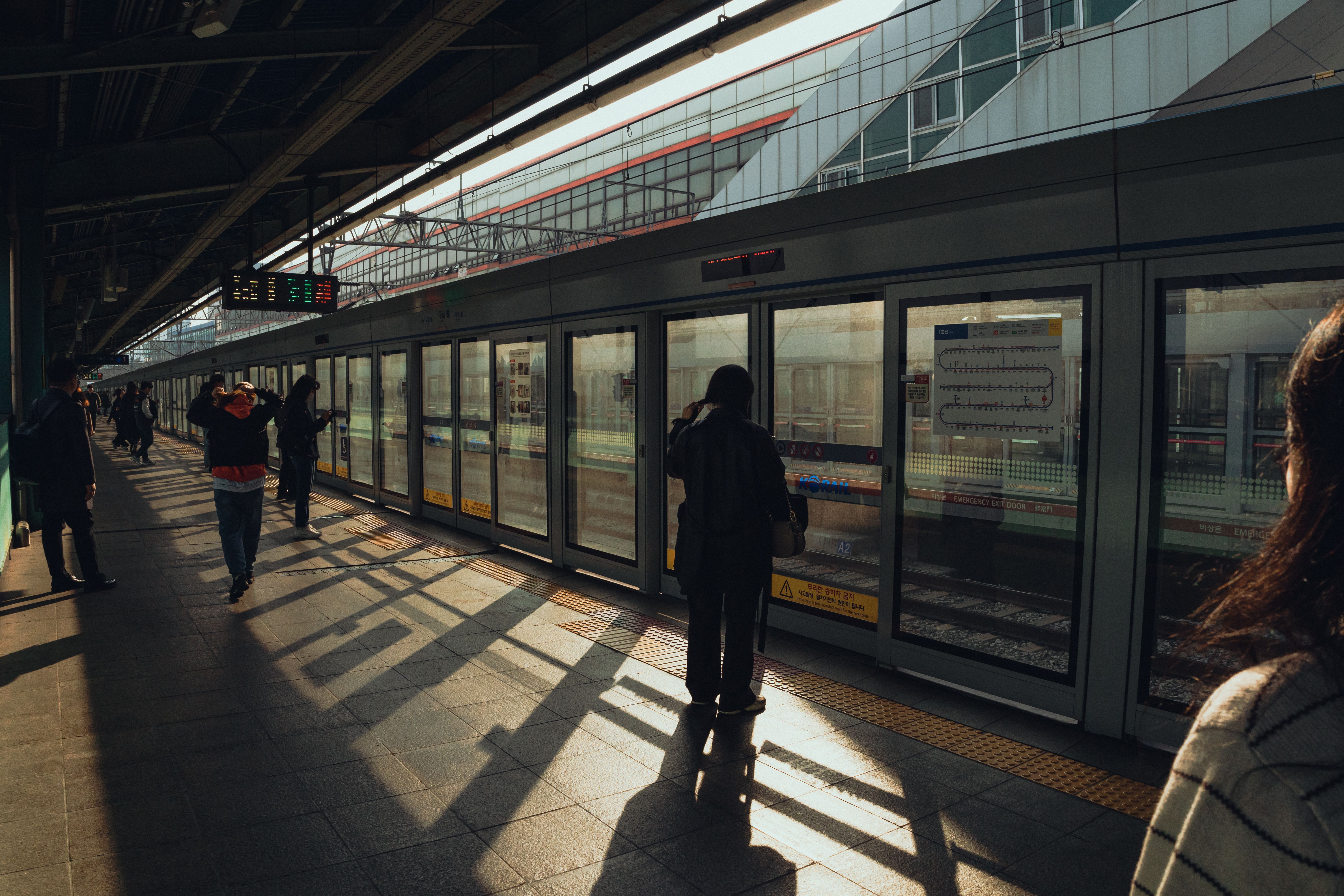 Seoul subway station scene with commuters in warm afternoon light, capturing urban life.