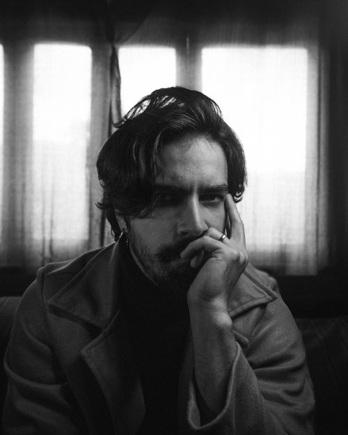 Free Black and white portrait of a thoughtful man sitting indoors with a pensive expression. Stock Photo
