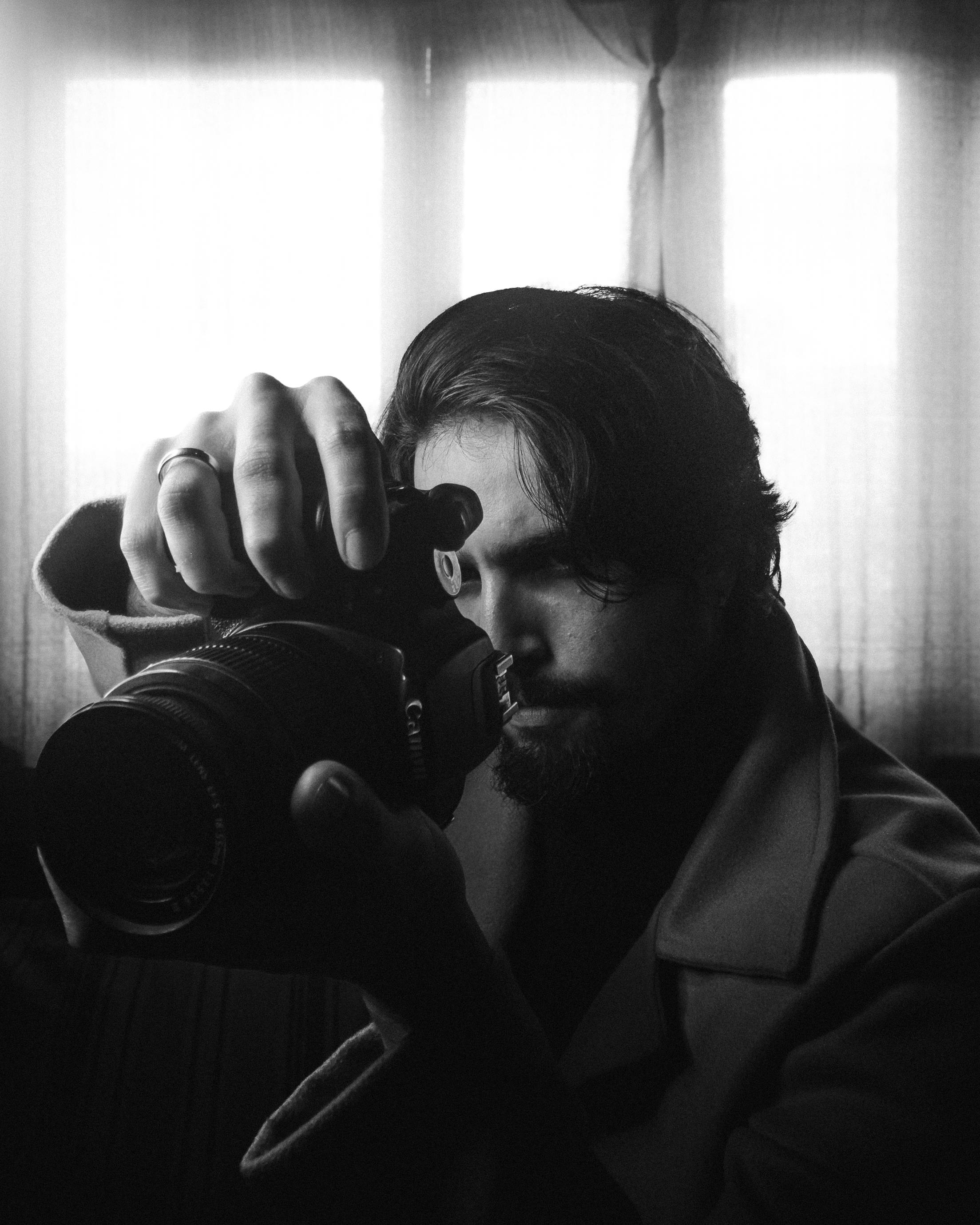 Stylish monochrome portrait of a male photographer capturing a moment indoors.