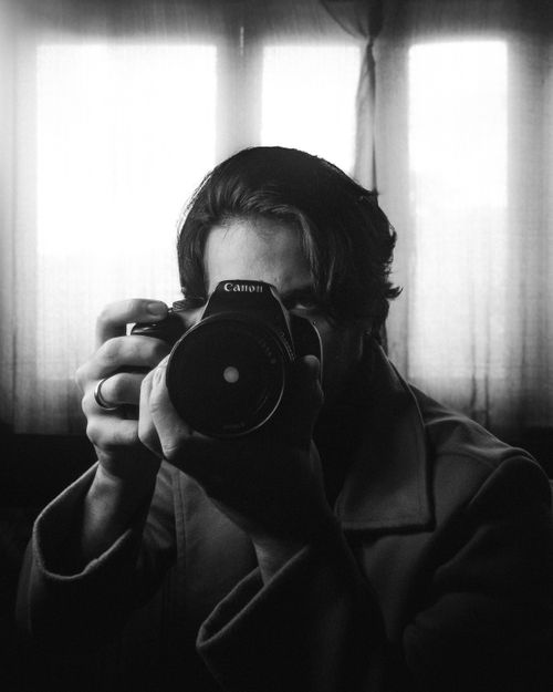 Free Moody black and white portrait capturing a photographer with a camera. Stock Photo
