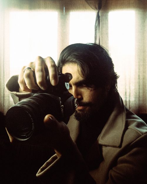 Free Artistic shot of a focused photographer using a camera indoors with soft lighting. Stock Photo