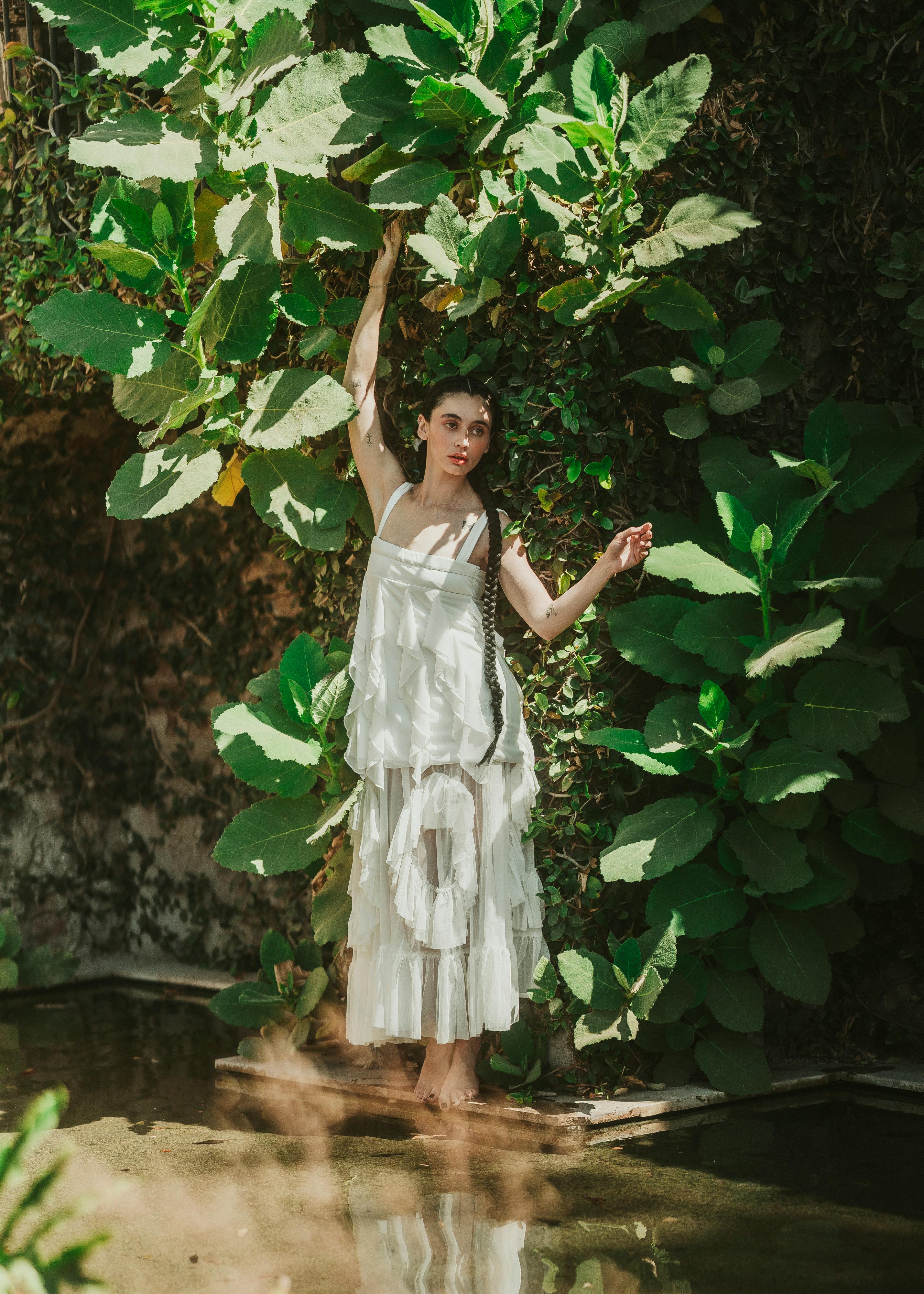 A woman elegantly posing amidst lush greenery, exuding a serene and natural vibe.