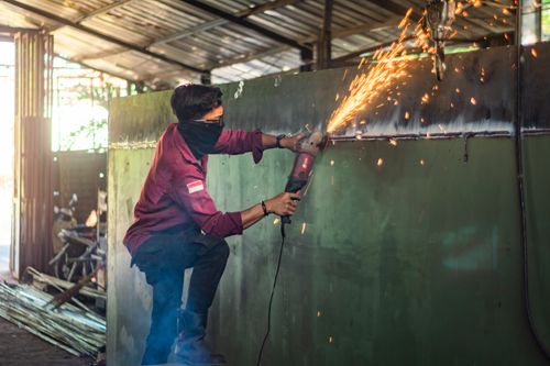 Free A worker in a workshop using a grinder on metal, emitting bright sparks in an industrial setting. Stock Photo
