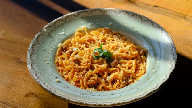 Plate of spaghetti carbonara garnished with basil in outdoor restaurant ambiance.