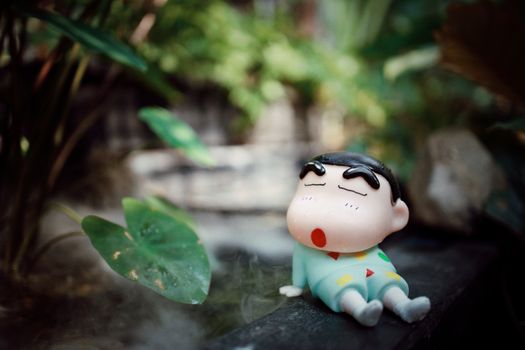 Charming cartoon character figurine relaxing in a peaceful garden setting.