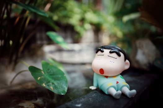 Cute toy figurine resting in a lush garden captures a playful and serene atmosphere.