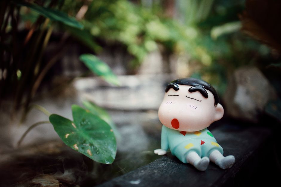 Cute toy figurine resting in a lush garden captures a playful and serene atmosphere.