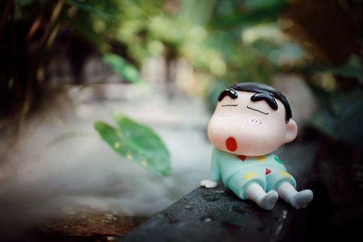 A cute toy figurine sleeping in a lush, natural outdoor setting.