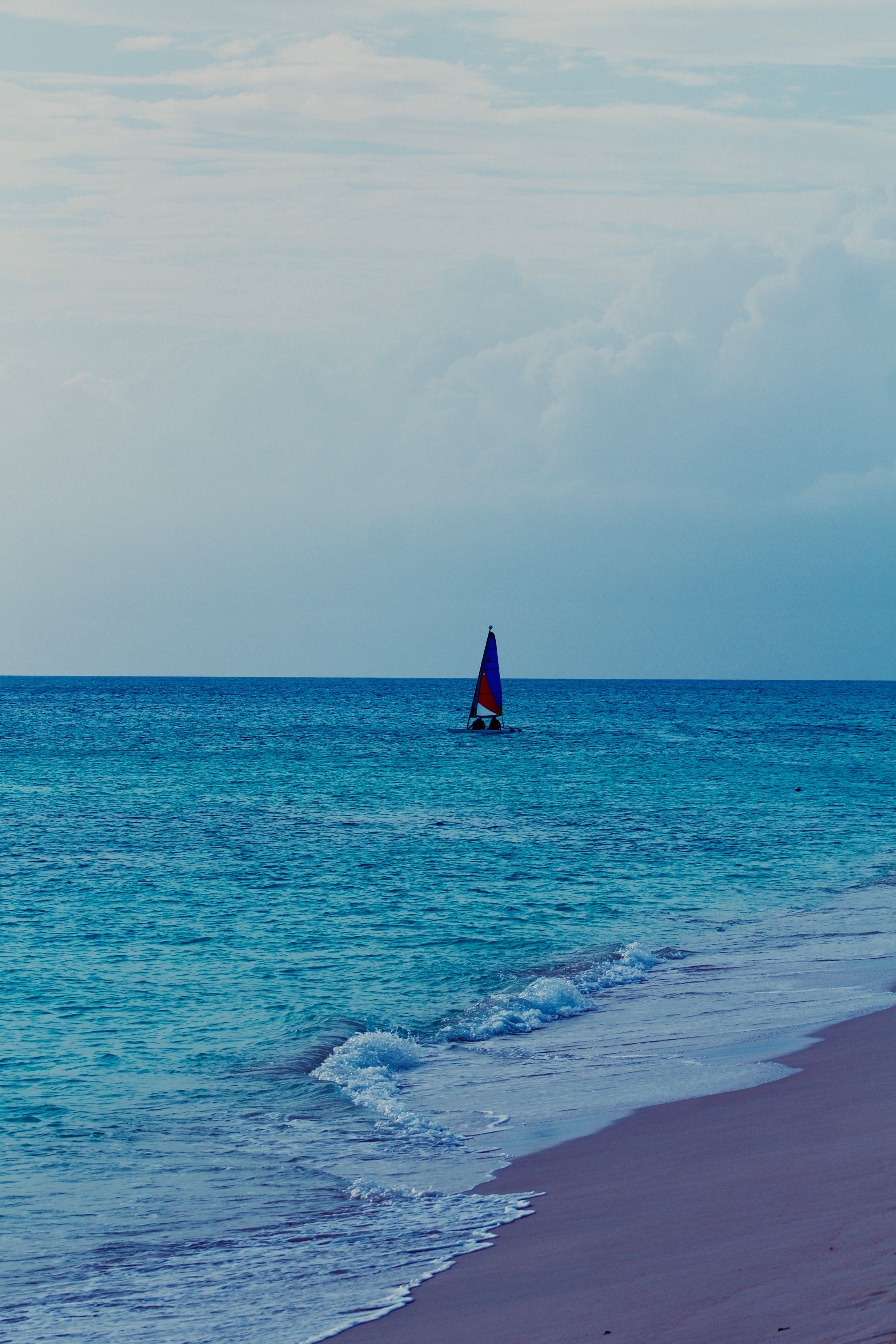 A sailboat on calm open ocean under a soft sunset sky, the kind of liveaboard life many Oahu boaters picture