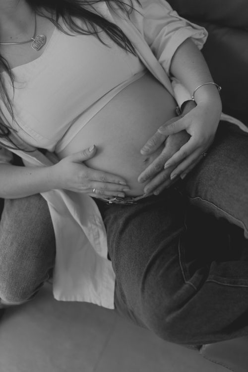 Free Intimate black and white photo of a pregnant couple gently holding the baby bump. Stock Photo