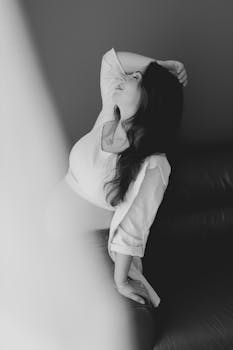 Black and white portrait of a woman in thoughtful pose on a sofa.
