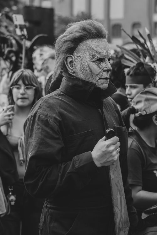Free A person in a spooky costume with others in the background during a street event. Stock Photo