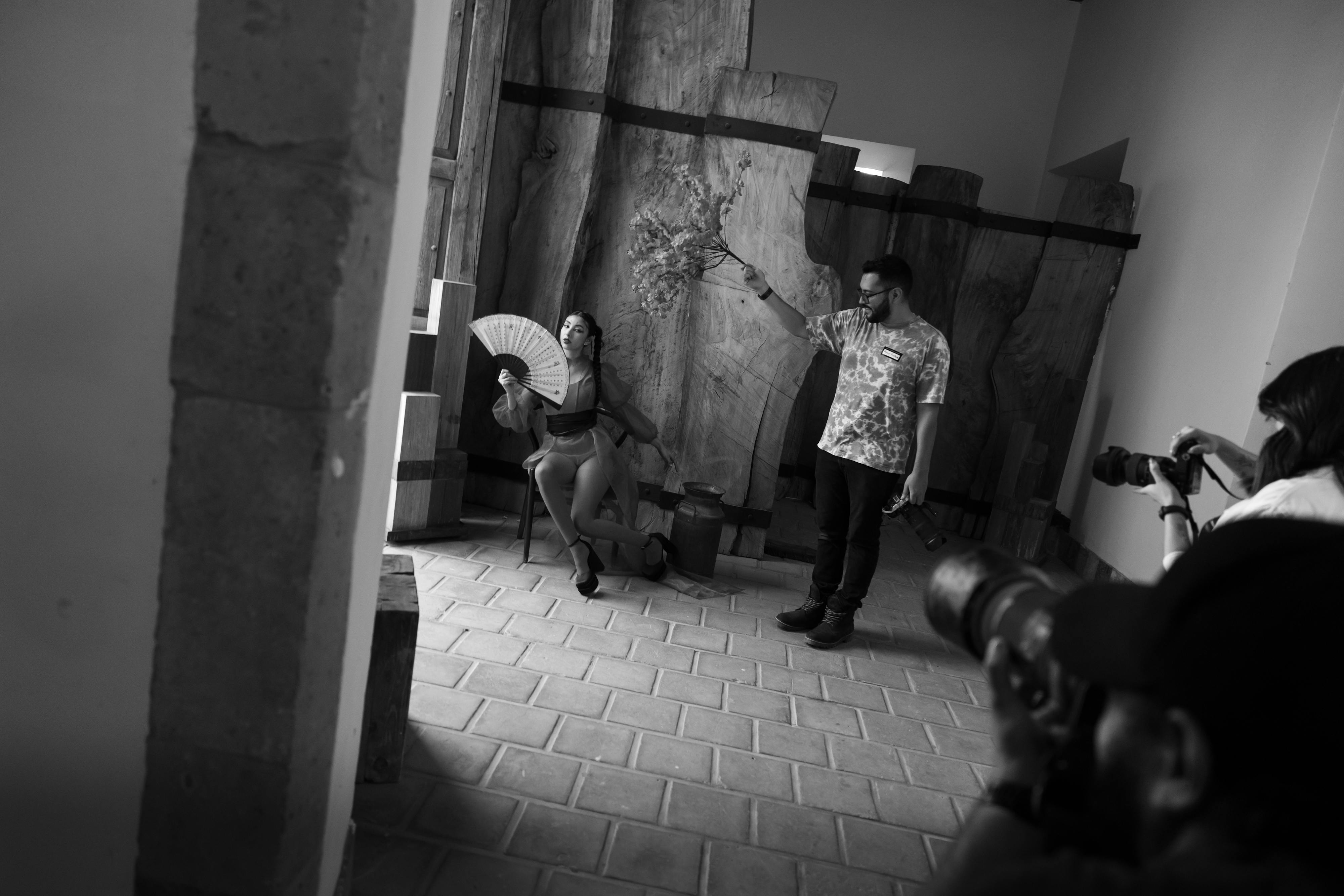 Free Artistic studio scene with photographers and model posing with fan in black and white. Stock Photo