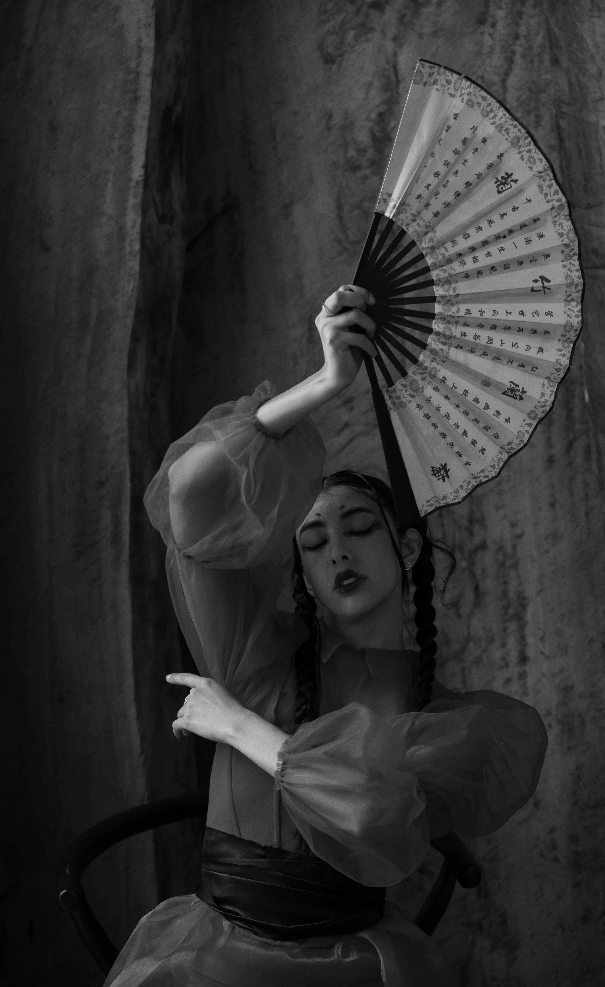 Elegant black and white portrait of a woman with a fan, evoking grace and mystery.