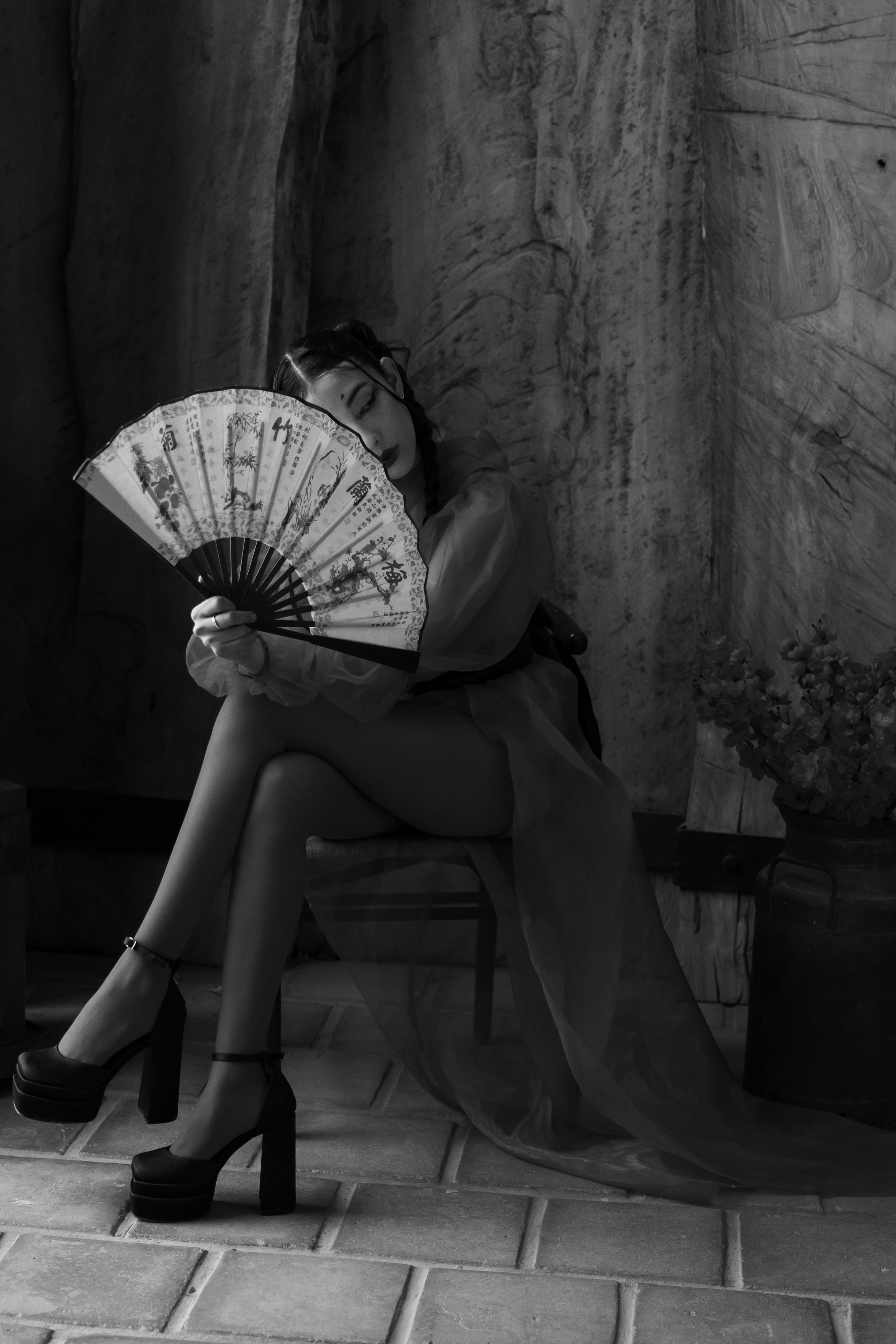 Free A stylish woman poses with a decorative fan in a black and white artistic portrait. Stock Photo
