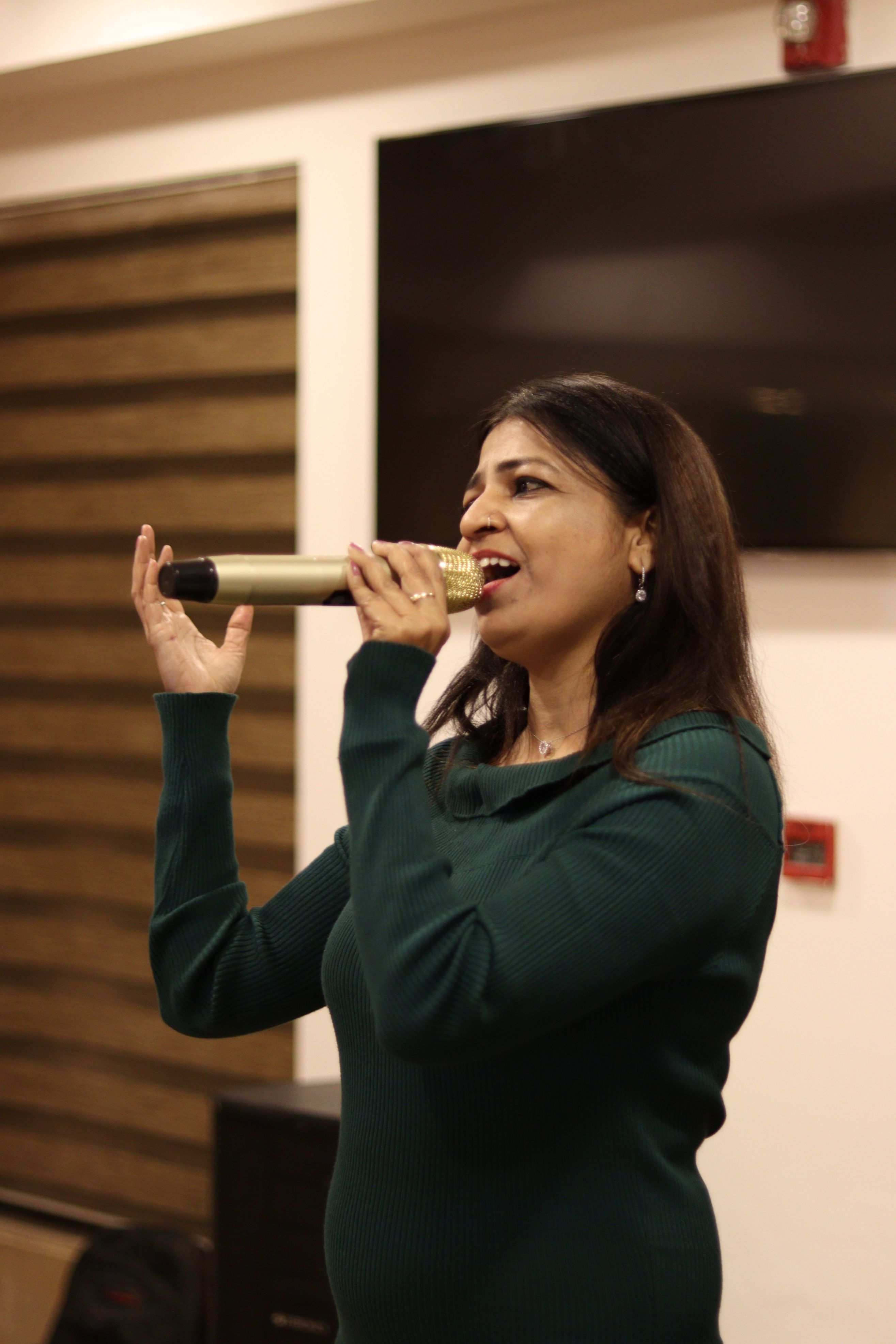 Adult woman passionately singing with a microphone indoors.