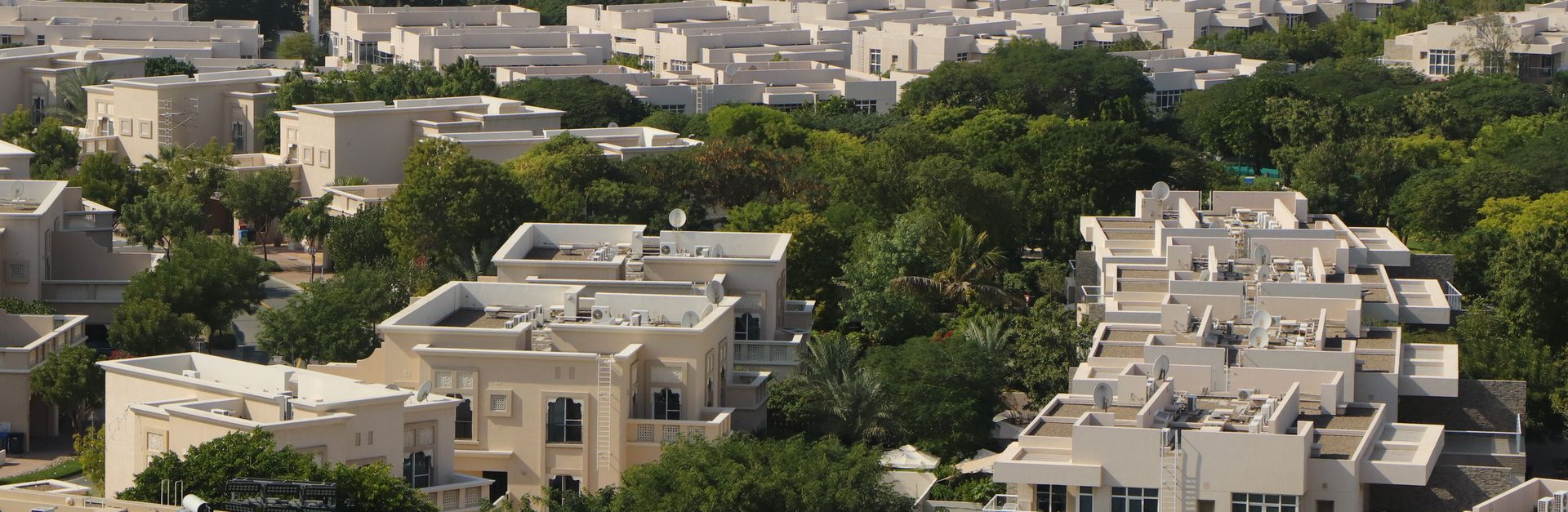 An expansive aerial view of a residential community surrounded by greenery in Dubai, UAE.
