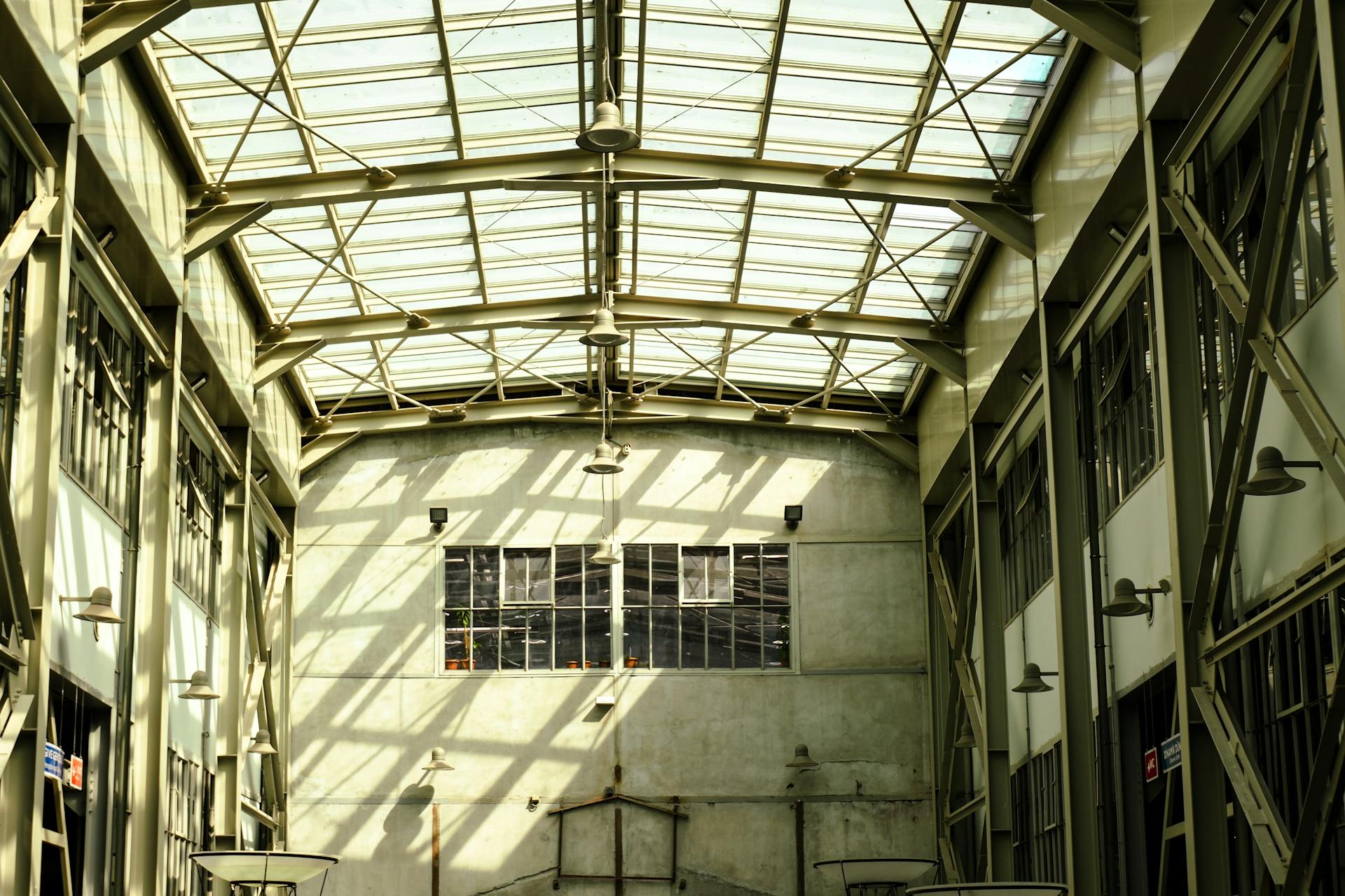 Spacious industrial warehouse interior with glass roof, allowing natural light to flood the space.