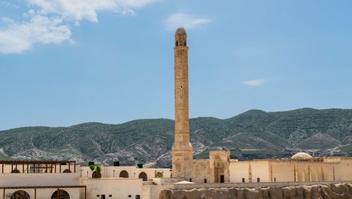 Free A stunning view of a historical mosque minaret set against a scenic mountain landscape under a clear blue sky. Stock Photo