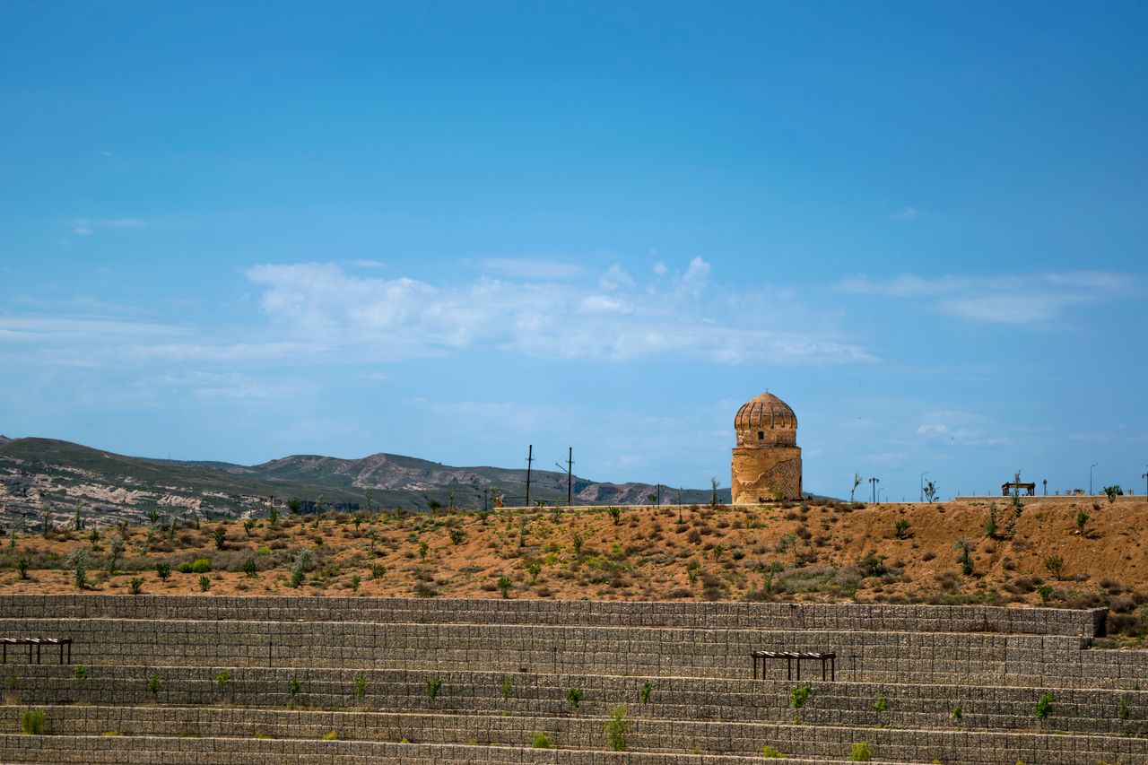 a solitary mosque minaret stands against a clear blue sky in a barren