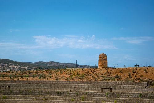 Free A solitary mosque minaret stands against a clear blue sky in a barren landscape. Stock Photo