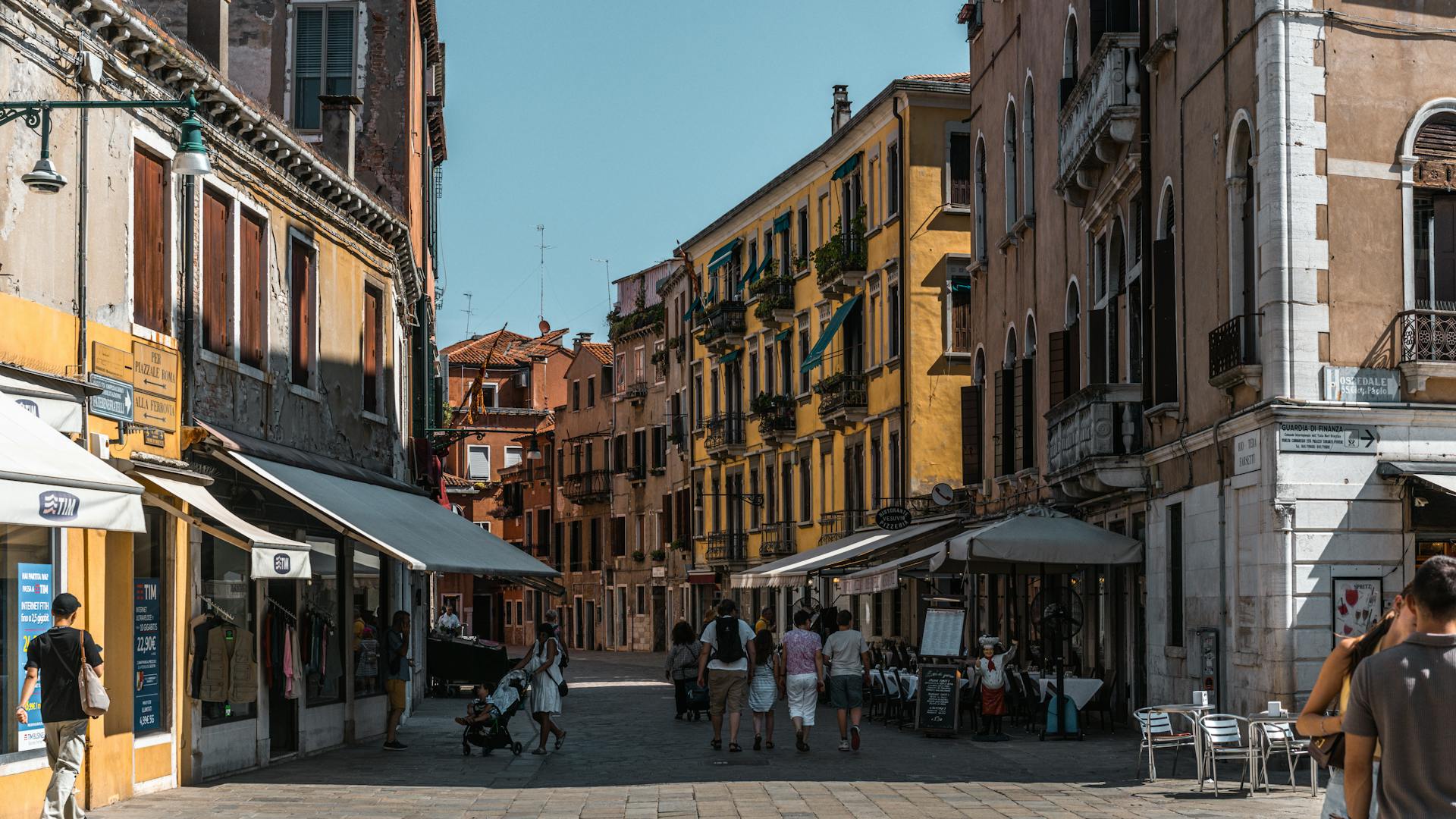 Charming summer street scene in Venice, Italy with colorful buildings and casual pedestrians.