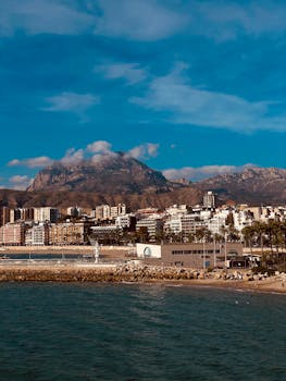 Beautiful coastal cityscape of Benidorm with mountains in the backdrop under a vibrant blue sky.