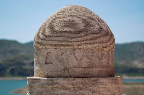 Free Ancient stone dome structure near a turquoise lake under clear blue skies. Stock Photo