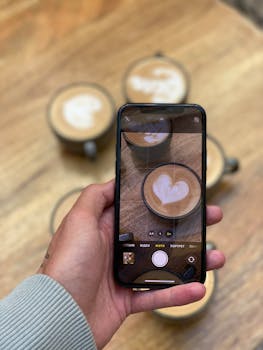 A person photographing latte art on cappuccinos, showcasing barista skills in a cozy cafe.