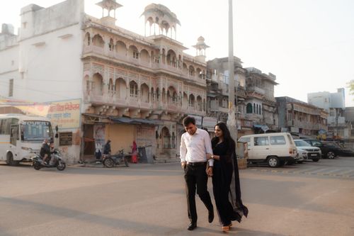 Free An Indian couple shares a romantic moment walking through a historic city with vintage architecture. Stock Photo